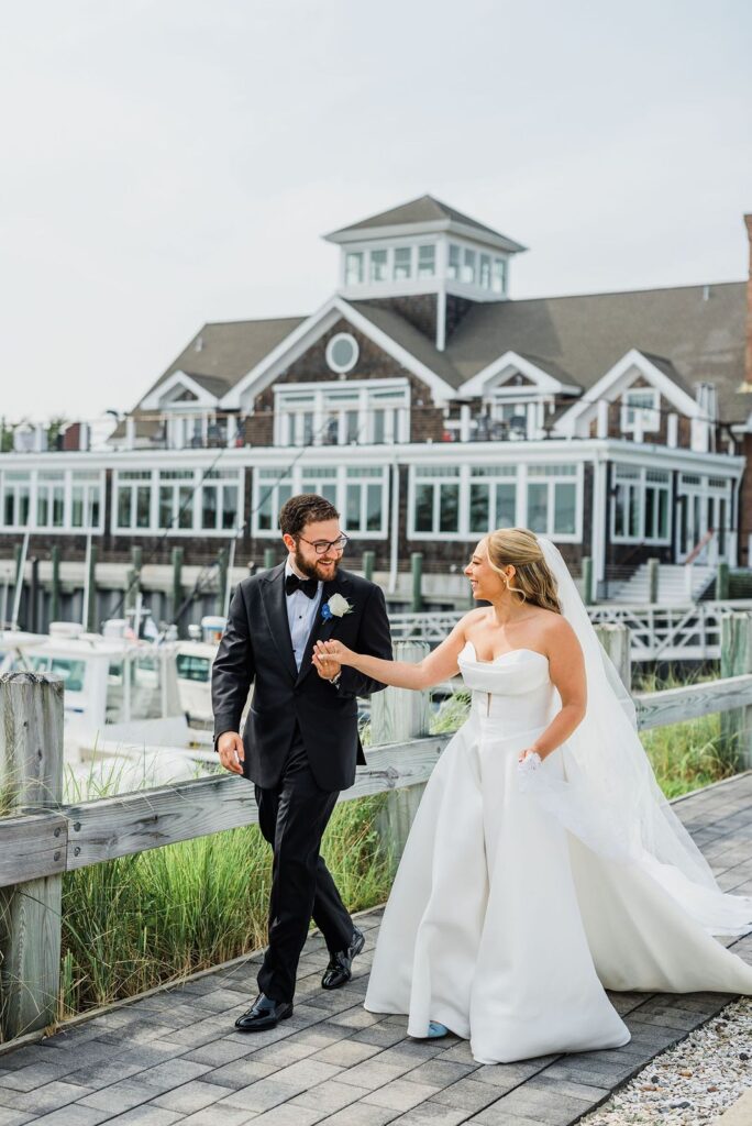 Newlyweds walking along marina at Peconic Bay Yacht Club