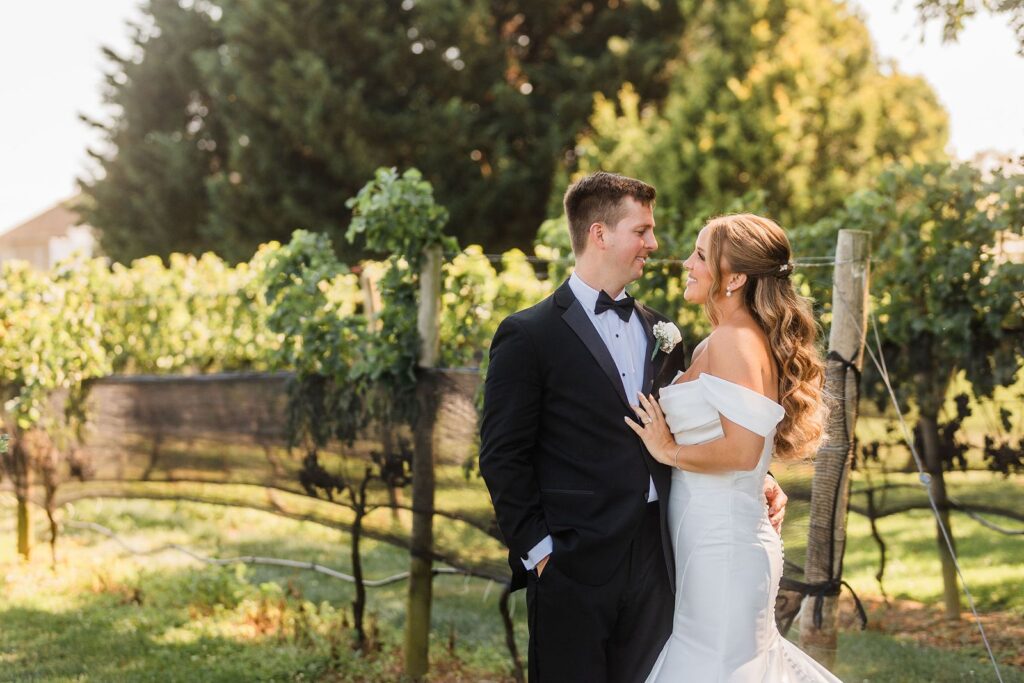 Bride and groom pose among vines at The Vineyards at Aquebogue